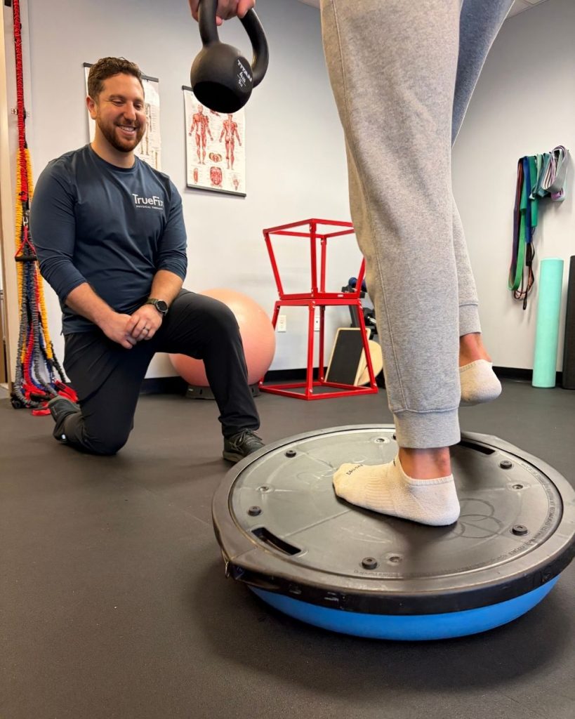 Physical therapist teaches a foot exercise at TrueFix Physical Therapy in Shawnee, KS