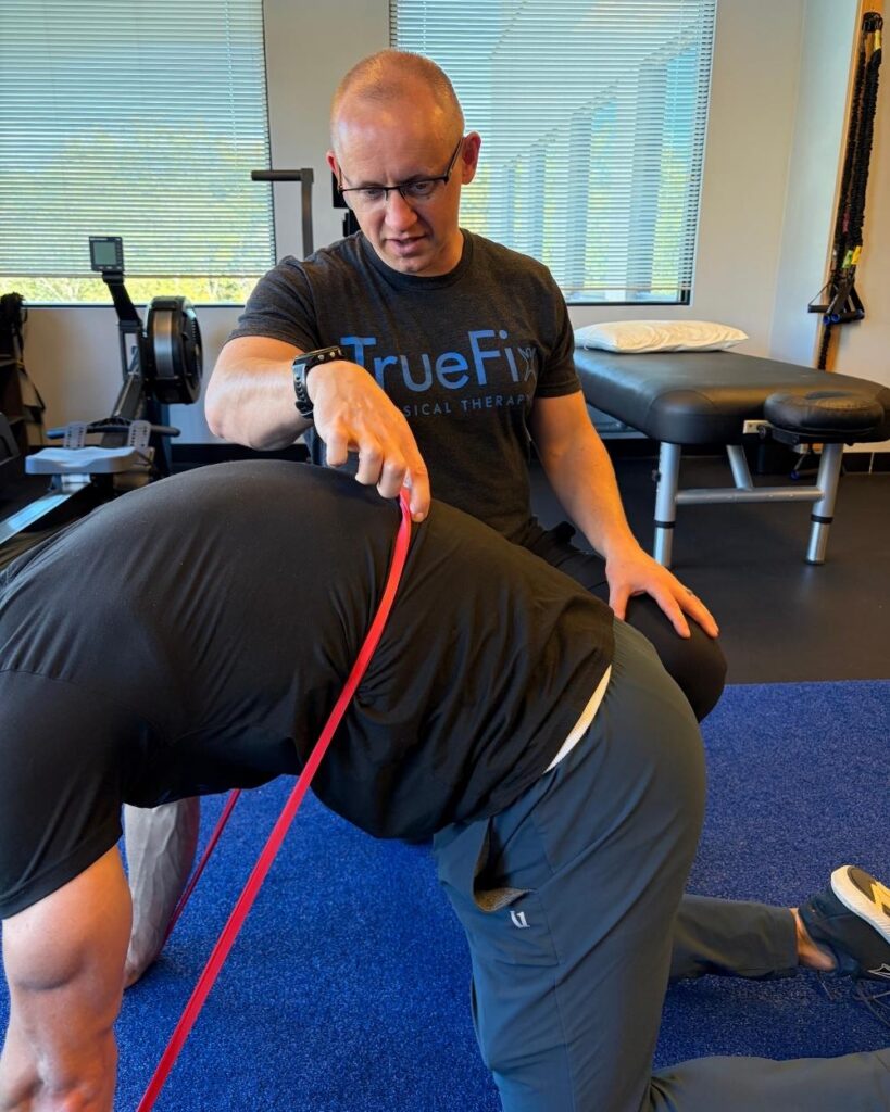 Physical therapist teaches a back exercise at TrueFix Physical Therapy in Overland Park, KS.