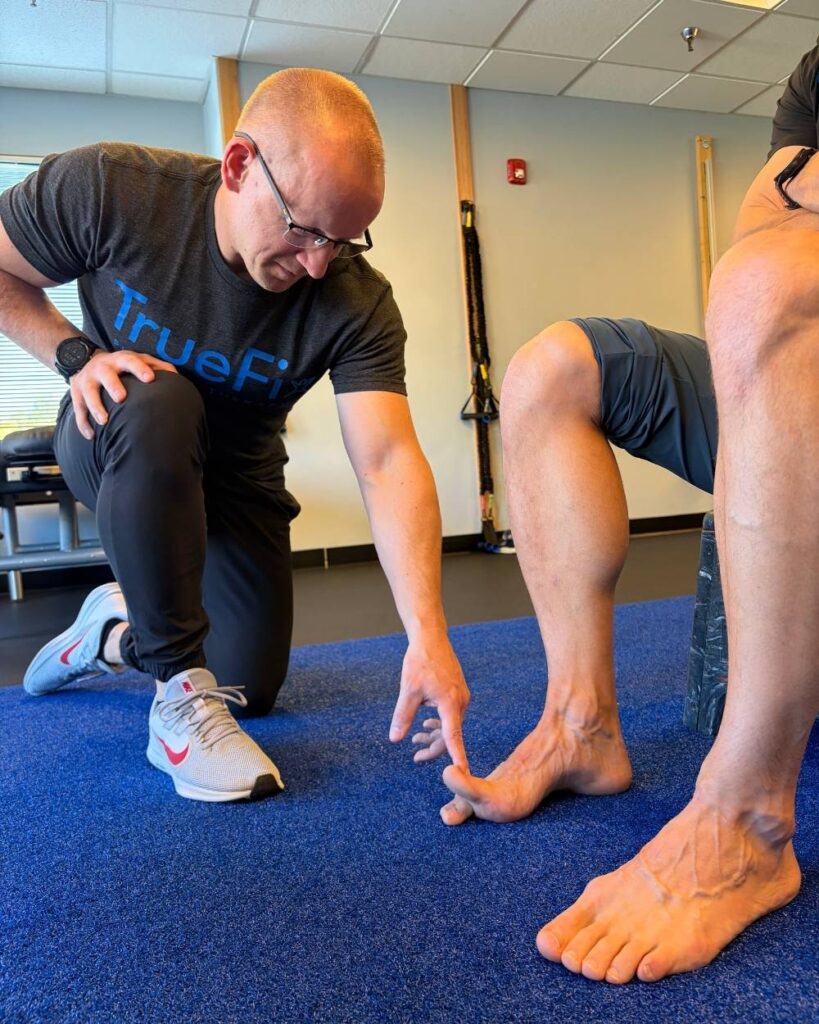 Physical therapist teaches a foot exercise at TrueFix Physical Therapy in Overland Park, KS.
