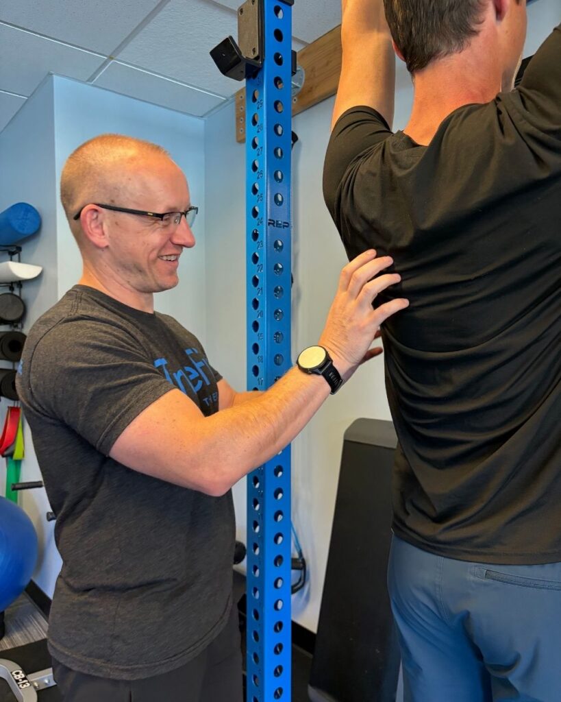 Physical therapist teaches a shoulder exercise at TrueFix Physical Therapy in Overland Park, KS.