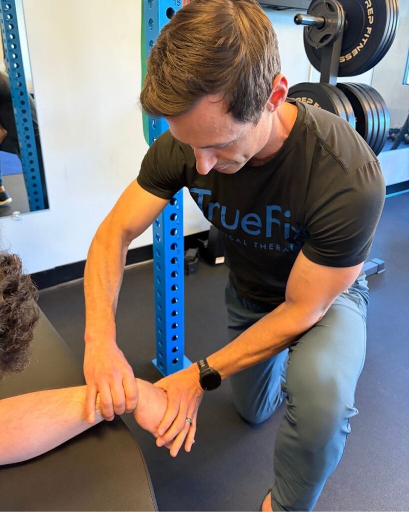 Physical therapist performs a wrist mobilization at TrueFix Physical Therapy in Overland Park, KS.